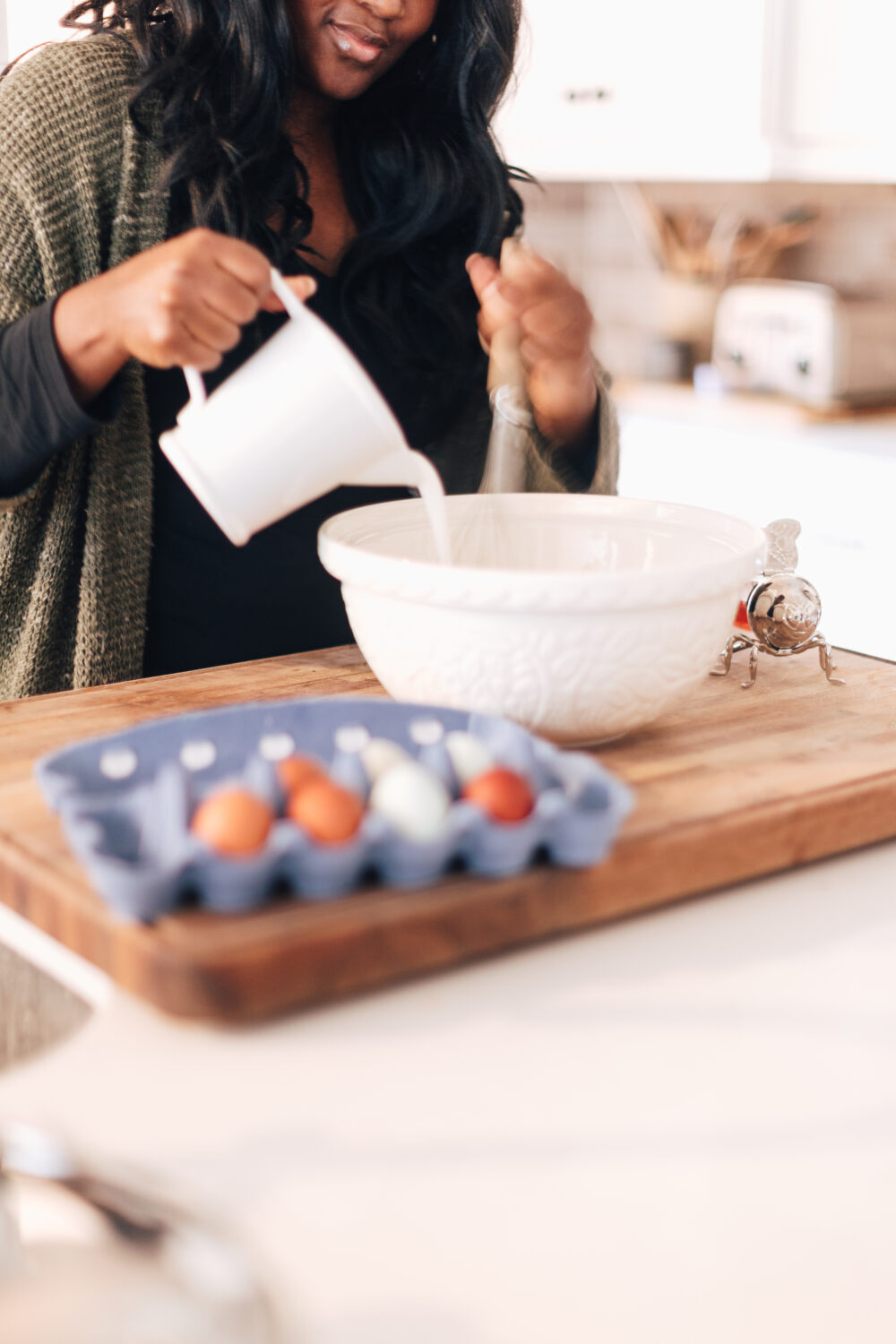 Making Morning Waffles for the Kids Make waffles with a white bowl. Woman pouring milk and other ingredients into a bowl.