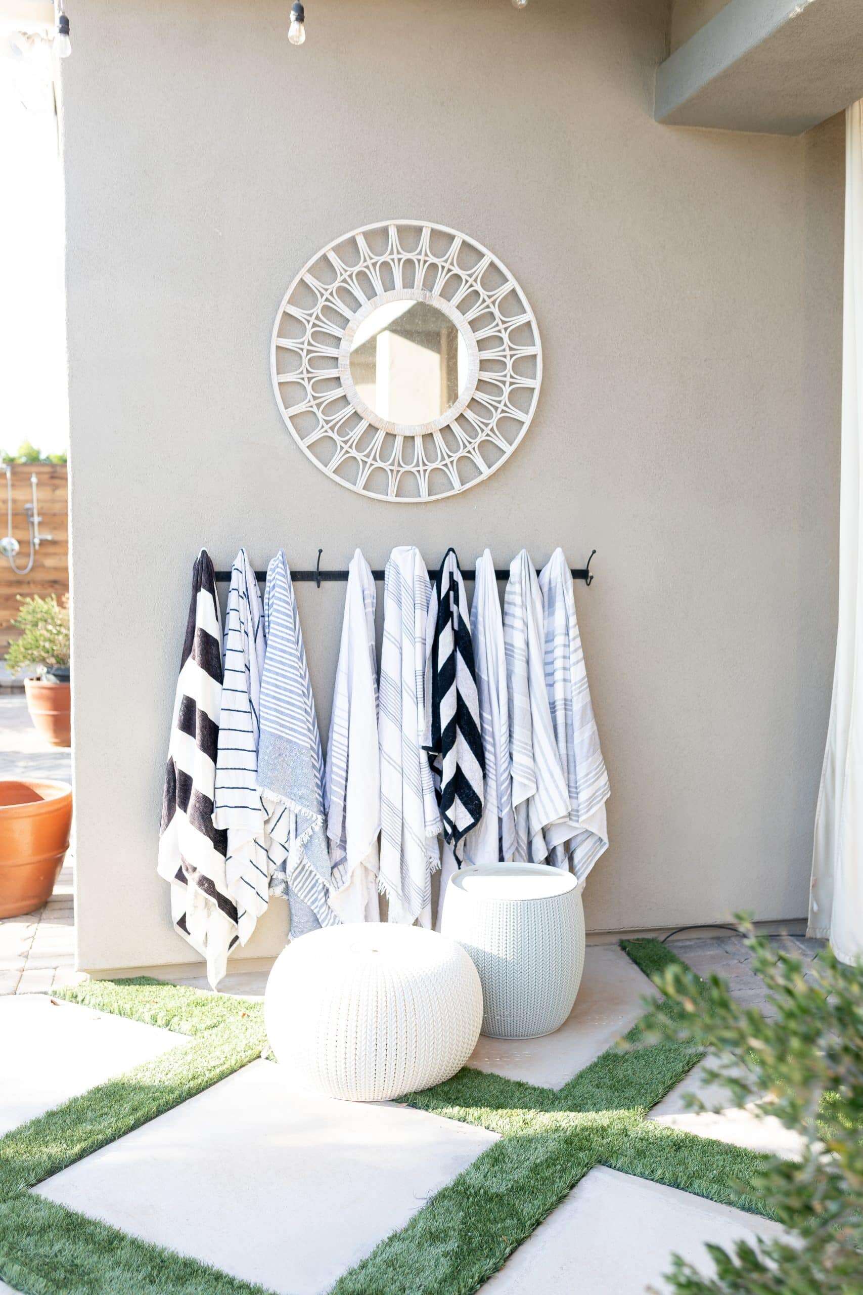 Outdoor pool towels hanging on a hook. Gray house with outdoor mirror