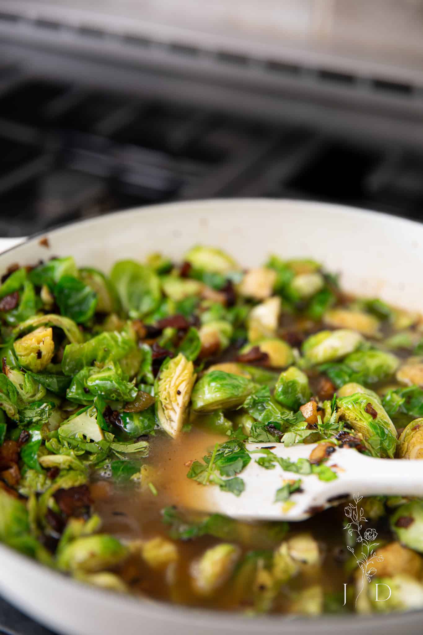 Overhead view of Brussels sprouts simmering in broth with garlic and peppers