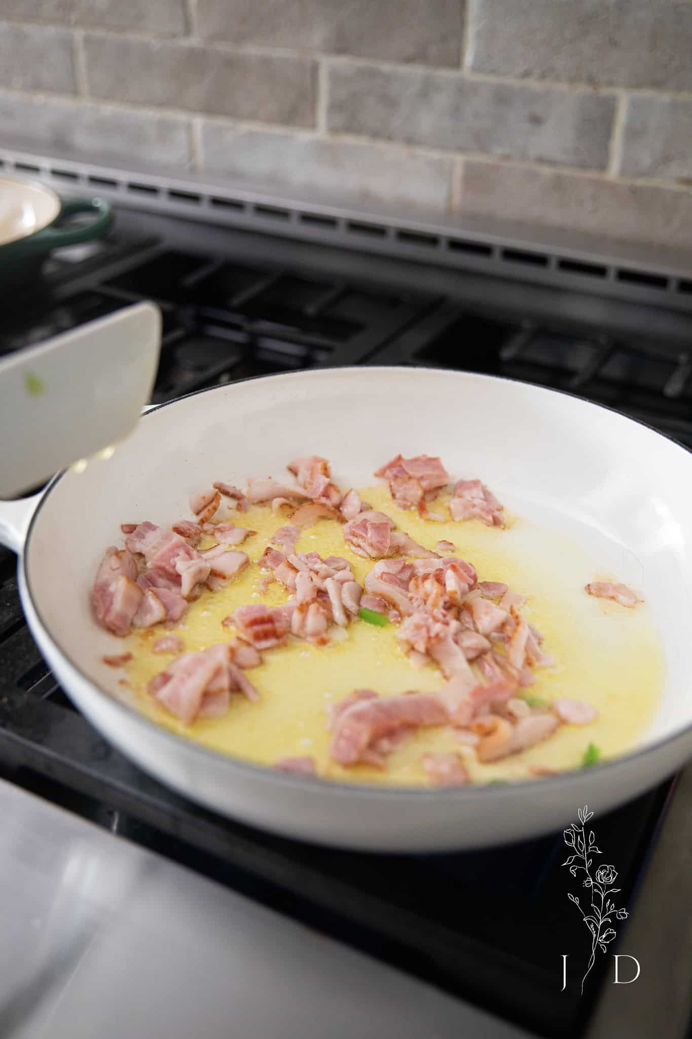 bacon in a pan simmering and cooking 