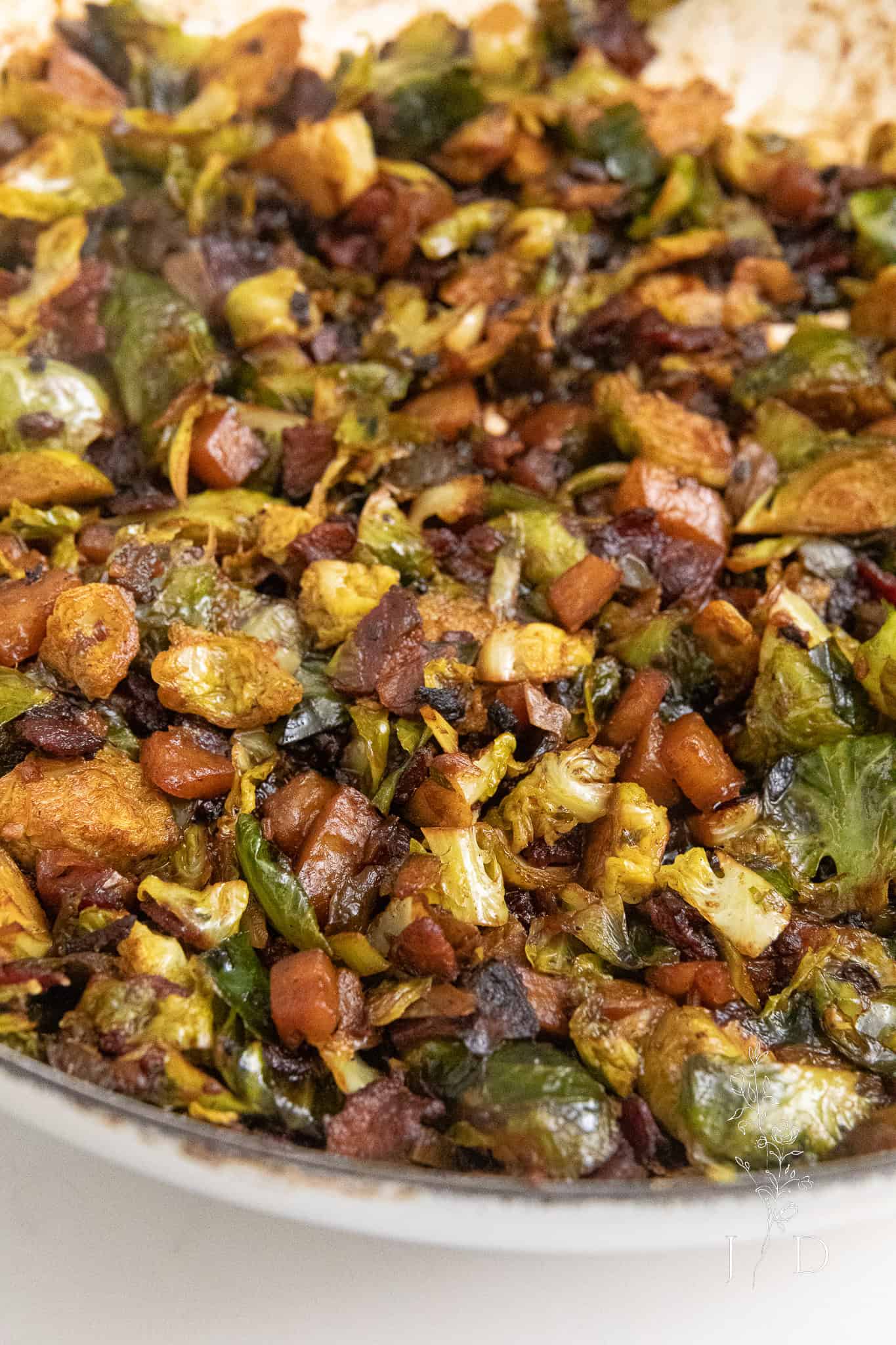 Close-up of braised Brussels sprouts with crispy bacon in a skillet